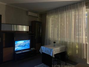 a living room with a table and a television at Piitota in Almaty +2 photos