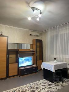 a living room with a table and a television at Piitota in Almaty
