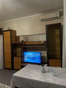 a living room with a table and a television at Piitota in Almaty