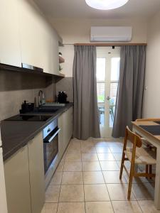 a kitchen with white cabinets and a table and a window at Litmus apartment 4 in Karlovasi