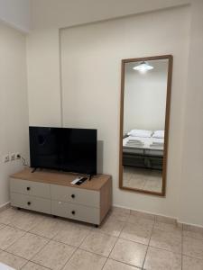a bedroom with a tv and a dresser with a mirror at Litmus apartment 4 in Karlovasi