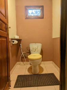 a bathroom with a toilet with a window and a rug at Villa Étage Z Irma in Antsiranana +26 photos