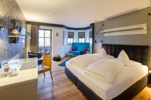 ein Hotelzimmer mit einem großen Bett und einem Schreibtisch in der Unterkunft Boutique Hotel Gams in Oberstdorf