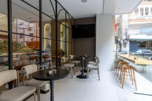 a restaurant with tables and chairs and windows at Golden City Boutique Hotel Tirana in Tirana