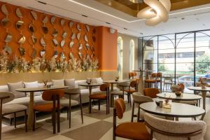 a restaurant with tables and chairs and a wall with plates at Golden City Boutique Hotel Tirana in Tirana