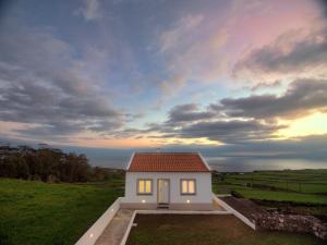 a small white house in a field with a sky at Casa Conchita in Angra do Heroísmo +14 photos