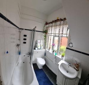 a bathroom with a tub and a toilet and a sink at Beautiful ground floor 2 bed flat in Camberley +5 photos