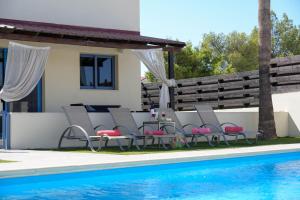 a group of chairs sitting next to a swimming pool at Villa Paradise Complex - Pyla Larnaca in Pyla