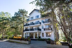 an exterior view of a white building with trees at Mimosa Forest Hotel Villa in Xuan An