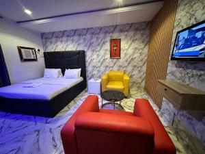 ein Hotelzimmer mit Bett, Sofa und Fernseher in der Unterkunft Desami Hotel in Omole