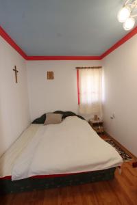 a bed in a room with a cross on the wall at Kicsipatak vendégház in Lunca de Sus