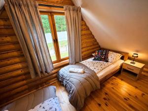 a bedroom in a log cabin with a bed and a window at Radawski Chill in Radawa