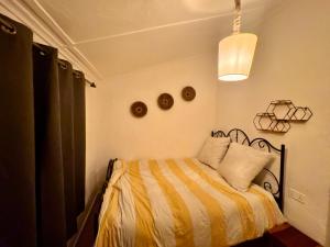 a bedroom with a bed with a yellow and white blanket at The Cozy Cottage in Ndola