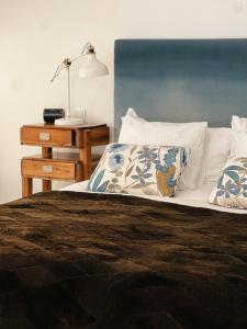 a bed with white pillows and a lamp on a table at A Capela - A Essência de Sintra in Sintra