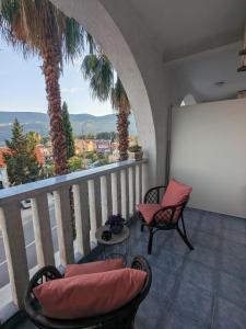 a balcony with two chairs and a whiteboard and palm trees at Azzurro in Igalo