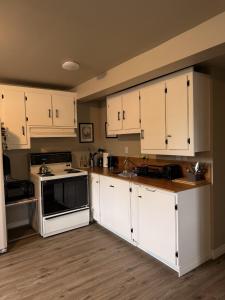 a kitchen with white cabinets and a stove at Eastpoint Cozy Apartment in St. John's +25 photos