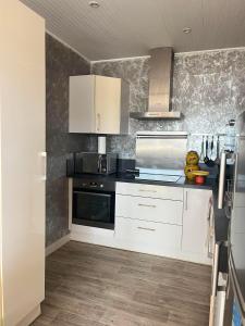a kitchen with white cabinets and a stove at logement de charme vue mer in Binic
