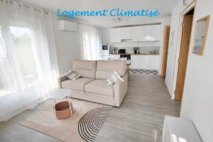 a living room with a couch and a kitchen at Petite maison de plain-pied in Coudures