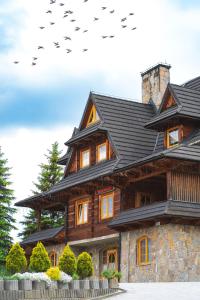 a large wooden house with birds flying around it at Willa Rohacze in Kościelisko