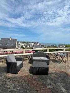 a group of chairs and tables on a patio overlooking the ocean at logement de charme vue mer in Binic