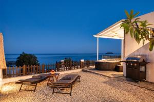 a patio with chairs and a grill and the ocean at Oniro Beach House in Archangelos