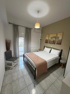 a bedroom with a large bed and a chair at Elenas Apartments in Plataria