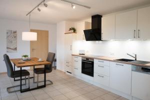 a kitchen with white cabinets and a wooden table at Ferienwohnung Hansen in Welschbillig