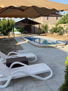 a pair of chairs and an umbrella next to a pool at Dreams House in Yengidzha