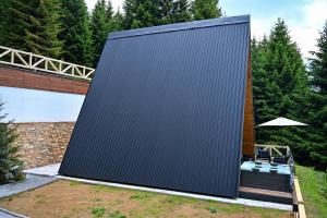 a large metal building with a bench and an umbrella at Tara mountain house Kopaonik in Kopaonik