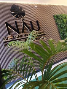 a sign on the side of a building with a plant at Nau Guest House & Restaurant in Iquitos
