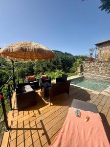 a deck with chairs and an umbrella next to a swimming pool at La Grange de Bosc -Ardèche verte - Proche train de Lamastre in Saint-Prix