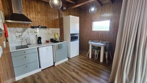 a kitchen with white cabinets and a table in it at Fernandes Guest House Green Bungalow in Ponte de Lima