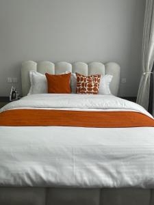 a bed with orange and white pillows on it at Cozy Nest in Marimbeti +11 photos