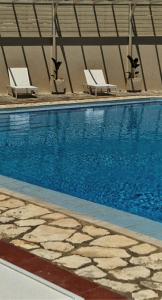 a swimming pool with two lounge chairs next to it at Abela Family Hotel in Argassi