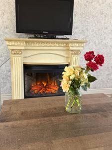 a vase of flowers on a table in front of a fireplace at Dreams House in Yengidzha