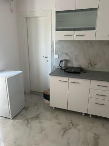 a kitchen with white cabinets and a white refrigerator at Studio Apartment Vukcevic 3 in Golubovci