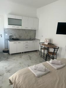 a kitchen with white cabinets and a table and a bed at Studio Apartment Vukcevic 3 in Golubovci