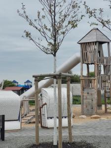 a playground with a tree and a slide at Ferienhaus Frieda in Friedrichskoog