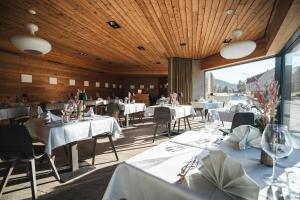 a restaurant with white tables and chairs and a large window at Pension Longhin Maloja - Self Check In in Maloja