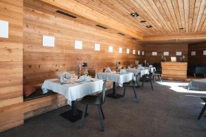 a dining room with white tables and wooden walls at Pension Longhin Maloja - Self Check In in Maloja