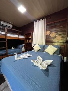 a bedroom with a blue bed with towels on it at Chalés Paradise in Atins