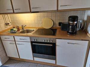 a kitchen with a sink and a stove at Haus Schildt, FeWo 2 in Duhnen