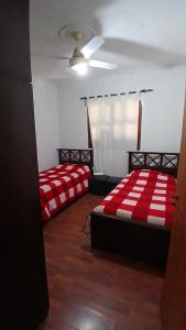 two beds in a room with red and white blankets at Temporario balcarce in Santo Tomé