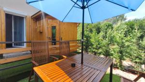 a wooden bench with an umbrella on a balcony at Rigófészek Apartmanház in Gárdony