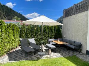 a patio with a table and chairs and an umbrella at Apart Alma in Pfunds