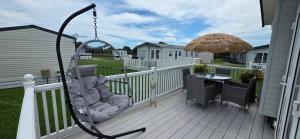 a swing on a porch with a table and an umbrella at Blue Lagoon Holiday ,Bude 79 in Cubert