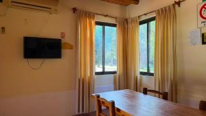 a dining room with a wooden table and two windows at Complejo Don Antonio in San Agustín de Valle Fértil