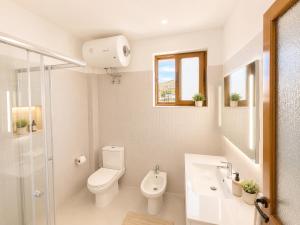 a white bathroom with a toilet and a sink at Portside Living in Sarandë +9 photos