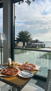 three pizzas on a table with a view of the ocean at Villa Marnero in Grigoleti