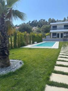a backyard with a swimming pool and a palm tree at Linen Sea Halkidiki in Kriopigi